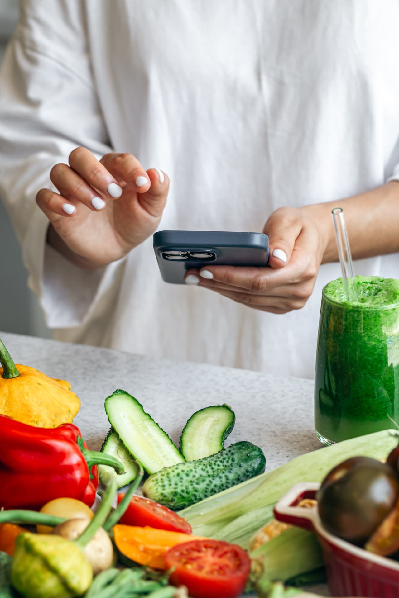 A woman using the Listek grocery list app on her phone while preparing fresh food.