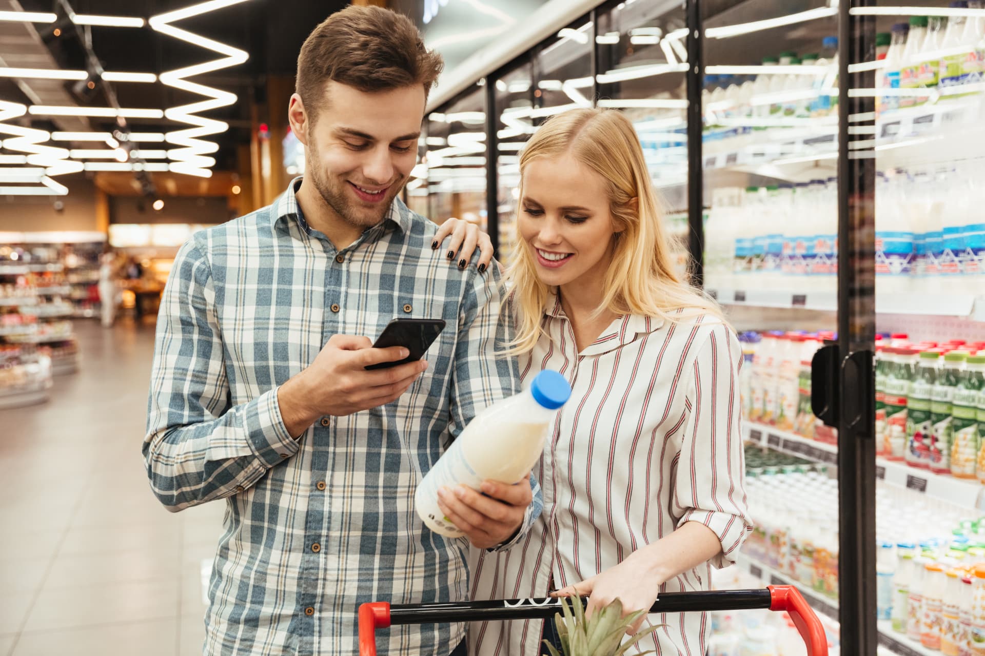 A couple checking their shared Listek shopping list on a phone in the supermarket.